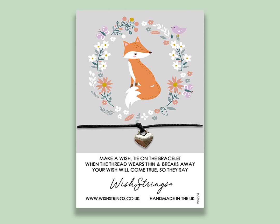 A corded silver heart charm mounted on a card with a picture of a fox.