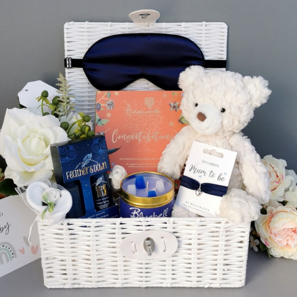 Mum to Be Hamper Gift with candle, pillow spray, bracelet, eye mask, chocolates and cream teddy bear in a white basket.