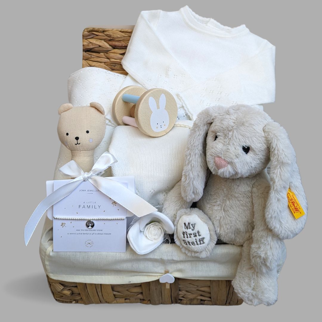Luxury baby hamper with white knit clothing set, steiff teddy, joma bracelet, organic hand rattle.