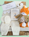 New baby hamper basket with gifts including  mr todd soft toy, Peter Rabbit book and white knit clothing set.