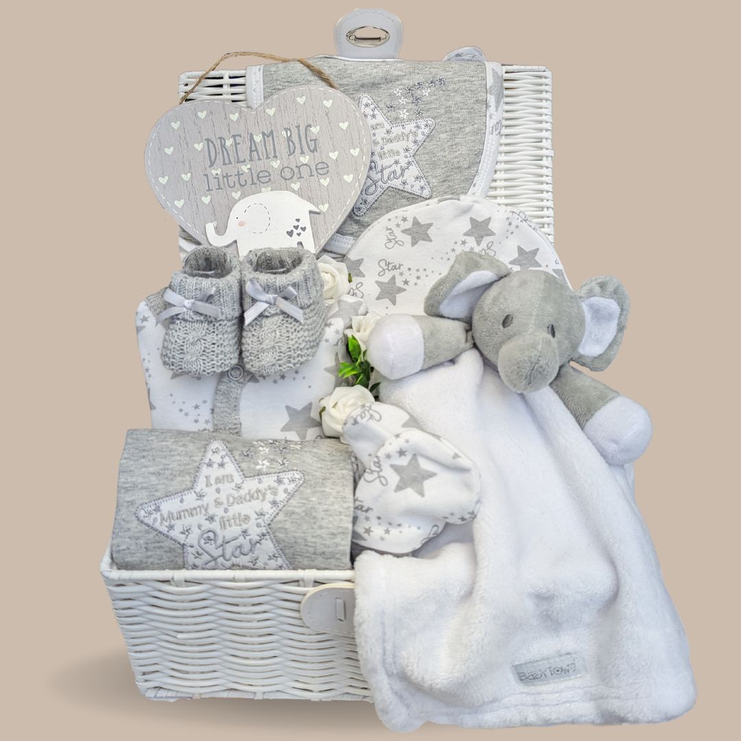 Baby hamper gifts in a grey hamper with white and grey gifts including grey baby clothes.