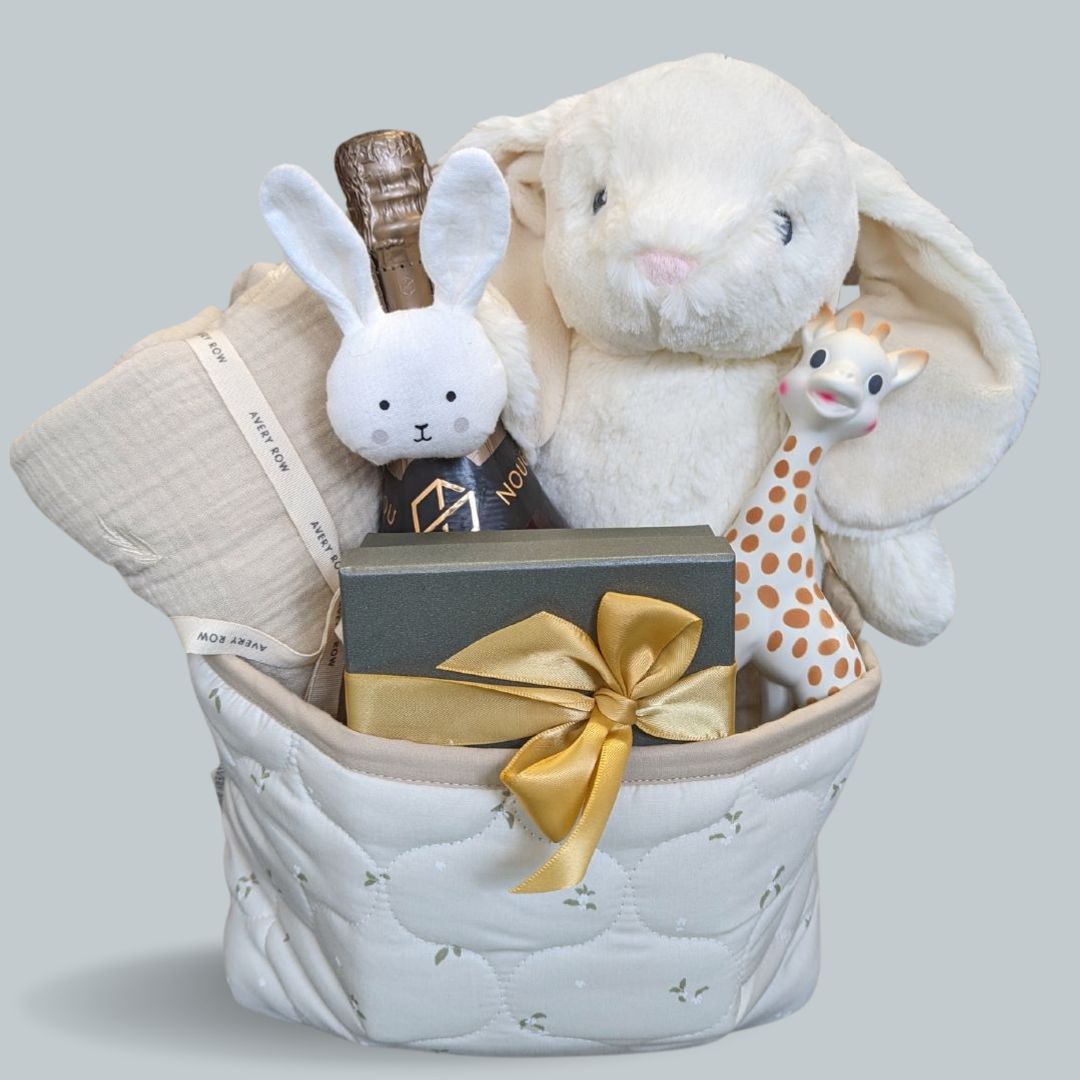 Beautiful new mum hamper basket filled with beautiful and practical delights. Presented in a quilted organic nappy basket with chocolate and non alcoholic wine for mum and treats for baby.