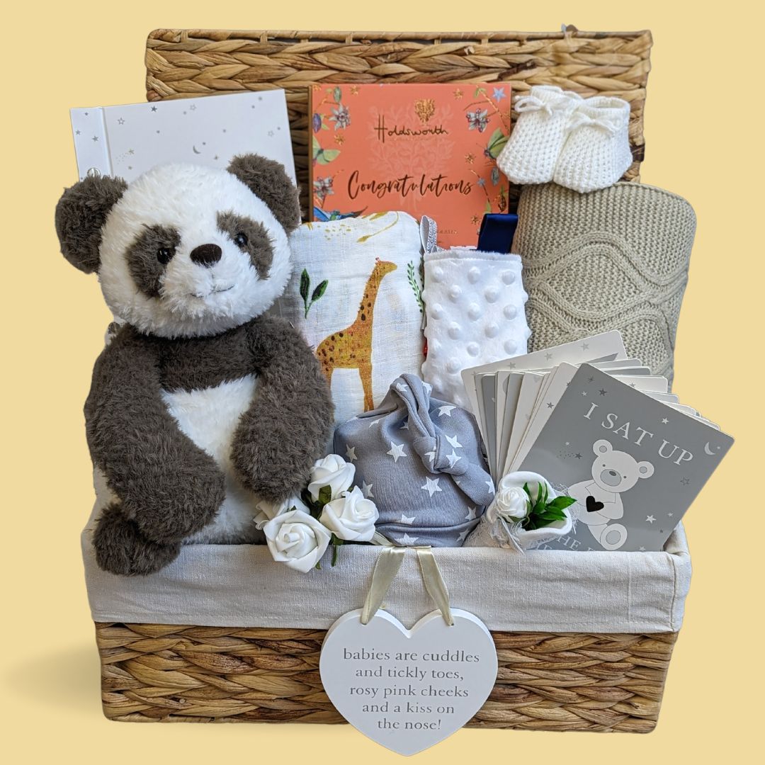 New mum hamper basket with panda bear soft toy, baby journal and milestone cards, baby blanket, baby hat and sensory taggie blanket.
