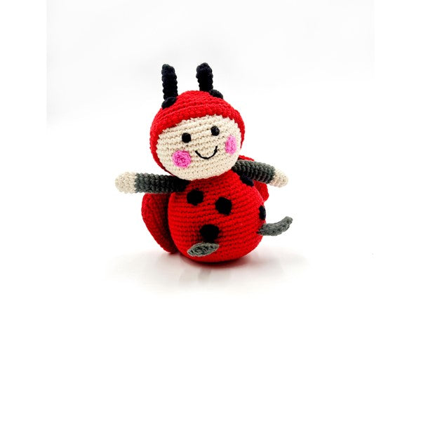 Handmade organic cotton ladybird rattle toy with a smiling face, black spots on the back, and black antennae.