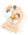 Rocket shaped wooden teether in muted tones.