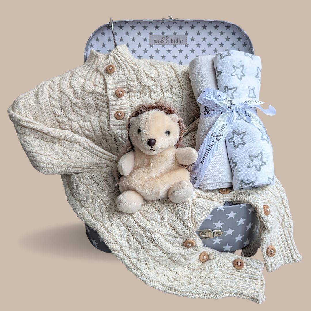 unisex baby gifts hamper with knit romper in beige, hedgehog soft toy and muslin wraps.