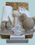 baby hamper basket with organic rattle, knit clothing set, booties and nursery plaque.