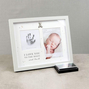 White handprint and photo frame standing beside a black ink pad.
